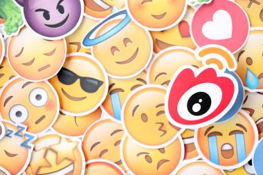 KYIV, UKRAINE - 20 Nisan 2024 Weibo logosu ve Emoji sarı yüzlü büyük çıkartmalar. Emoji, elektronik mesajlarda ve web sayfalarında kullanılan ve metne gömülü bir resim veya gülen yüzdür.