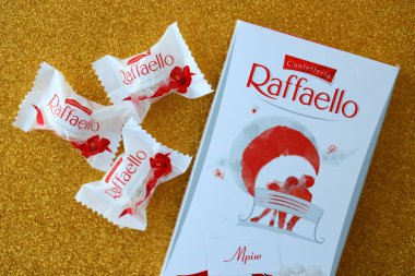 KYIV, UKRAINE - 20 Nisan 2024 Ferrero Raffaello premium tatlılar İtalyan çikolatacı Ferrero SpA tarafından altın arka planda üretildi. Raffaello şekerlemeleri küresel bir hindistan cevizi badem şekerlemesidir.