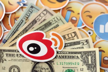 KYIV, UKRAINE - 20 Nisan, 2024 Weibo logosu ve birçok kullanım parası. Birçok emoji reaksiyonuna ilişkin ünlü sosyal ağ platformu ve dolar banknotlarının sembolü