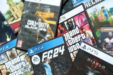 KYIV, UKRAINE - 26 Haziran 2024 Sony Playstation 5 ve 4 konsolu için video oyunları yığını. Birçok popüler video oyunu disk kutusu kapanıyor