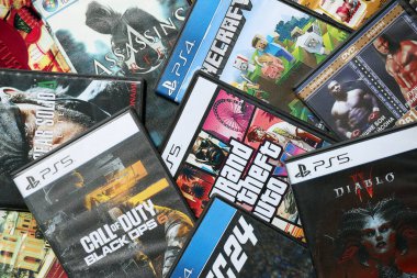 KYIV, UKRAINE - 26 Haziran 2024 Sony Playstation 5 ve 4 konsolu için video oyunları yığını. Birçok popüler video oyunu disk kutusu kapanıyor
