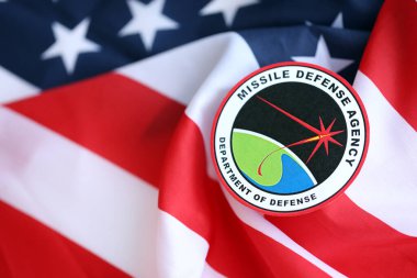 KYIV, UKRAINE - JUNE 26, 2024 Department of Defense Missile Defense Agency coat of arms sticker on folded US flag close up clipart