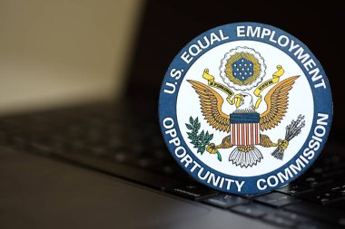 KYIV, UKRAINE - JUNE 26, 2024 U.S. Equal Employment Opportunity Commission coat of arms sticker on silver laptop close up clipart