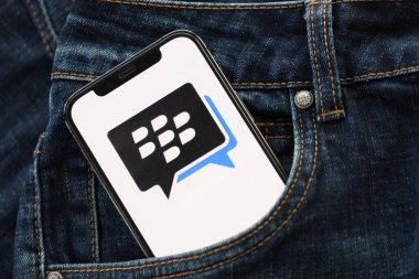 KYIV, UKRAINE - 1 Nisan 2024 Blackberry kurye simgesi kot pantolon cebinde akıllı telefon ekranında. Uygulama logosuna sahip iPhone görüntüsü. Moda görünümlü kotların cebinde gizleniyor.