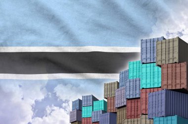 Botswana flag and big stack of shipping cargo containers in docks with sky background close up clipart