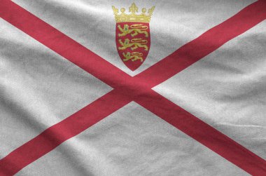 Jersey flag depicted on folded wavy fabric of old cloth close up clipart