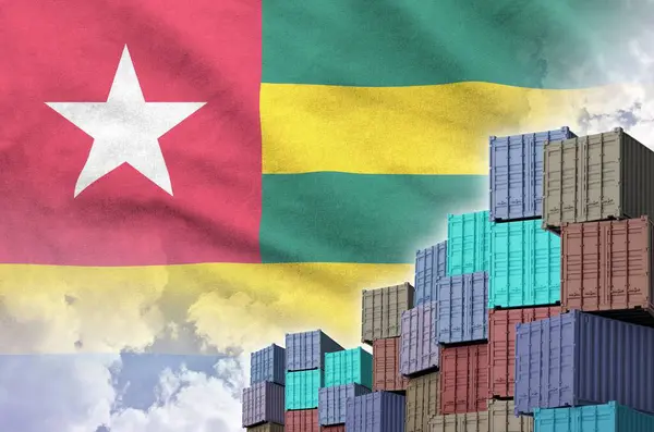 stock image Togo flag and big stack of shipping cargo containers in docks with sky background close up