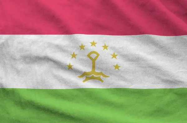 Stock image Tajikistan flag depicted on folded wavy fabric of old cloth close up