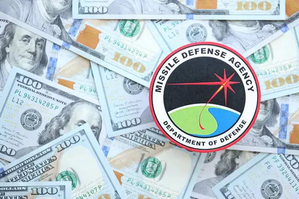 stock image KYIV, UKRAINE - JUNE 26, 2024 Department of Defense Missile Defense Agency coat of arms on big amount of US dollar banknotes close up