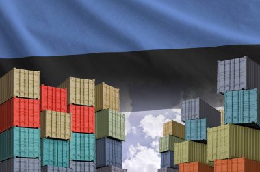 Estonia flag and big stack of shipping cargo containers in docks with sky background close up clipart