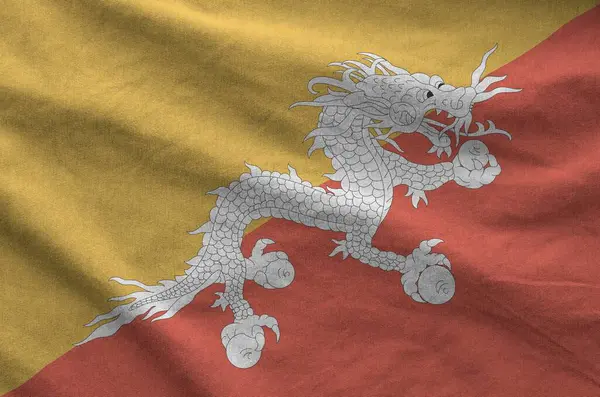 stock image Bhutan flag depicted on folded wavy fabric of old cloth close up