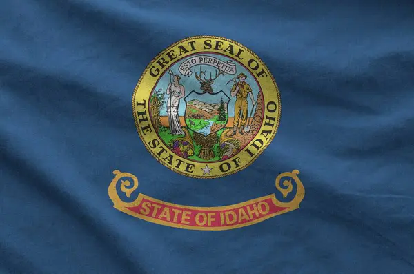 stock image Idaho US state flag depicted on folded wavy fabric of old cloth close up