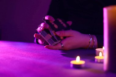 KYIV, UKRAINE - 10 Temmuz 2024 Tarot okuyucusu tarot kartı seçiyor. Karanlık odada mum ışığı. Tarot okuyucusu veya falcı okuma ve tahmin yakın yakın