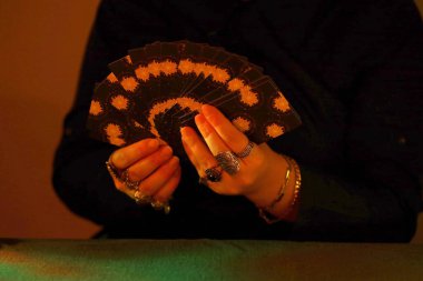 KYIV, UKRAINE - 10 Temmuz 2024 Tarot okuyucusu tarot kartı seçiyor. Karanlık odada mum ışığı. Tarot okuyucusu veya falcı okuma ve tahmin yakın yakın