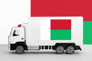 Madagascar flag depicted on side wall of white delivery van close up. Shipping and local delivery concept clipart