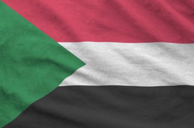 Sudan flag depicted on folded wavy fabric of old cloth close up clipart