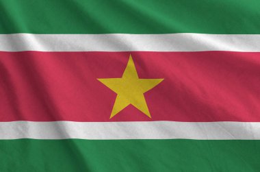 Suriname flag depicted on folded wavy fabric of old cloth close up clipart