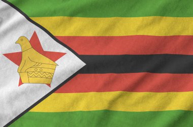 Zimbabwe flag depicted on folded wavy fabric of old cloth close up clipart