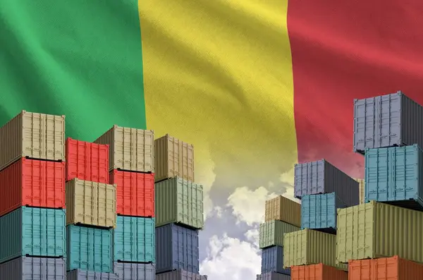 stock image Mali flag and big stack of shipping cargo containers in docks with sky background close up