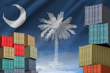 Güney Carolina eyalet bayrağı ve rıhtımlarda arka planda bulunan büyük kargo konteynırları.