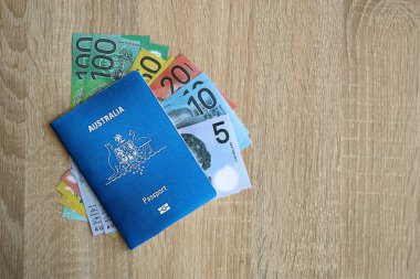 KYIV, UKRAINE - 10 Temmuz 2024 Avustralya mavi seyahat pasaportu ve ahşap arka planda para yakın plan