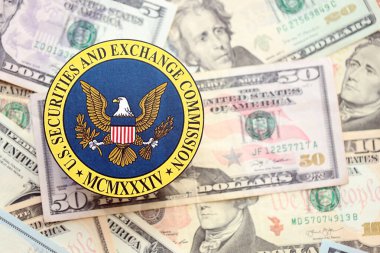 KYIV, UKRAINE - 26 Haziran 2024 ABD Menkul Kıymetler ve Borsa Komisyonu arması büyük miktarda ABD doları banknotları yakın çekim