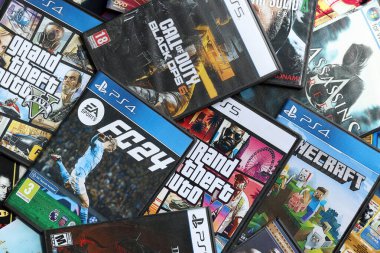 KYIV, UKRAINE - 26 Haziran 2024 Sony Playstation 5 ve 4 konsolu için video oyunları yığını. Birçok popüler video oyunu disk kutusu kapanıyor