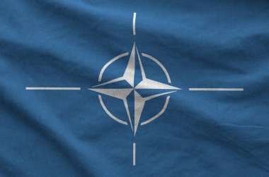 Eski kumaşın katlanmış dalgalı kumaşında NATO bayrağı tasvir edilmiştir.