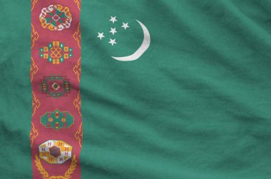 Turkmenistan flag depicted on folded wavy fabric of old cloth close up clipart