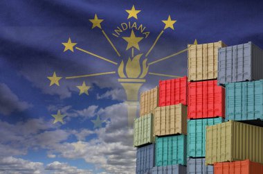 Indiana US state flag and big stack of shipping cargo containers in docks with sky background close up clipart