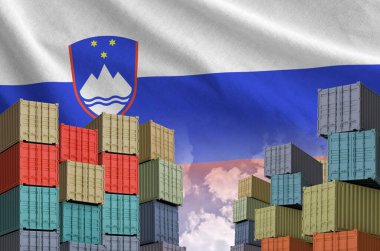 Slovenia flag and big stack of shipping cargo containers in docks with sky background close up clipart