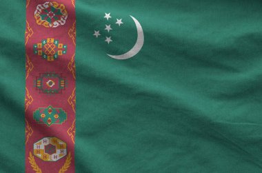 Turkmenistan flag depicted on folded wavy fabric of old cloth close up clipart