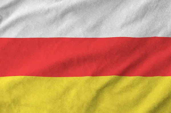 Stock image South Ossetia flag depicted on folded wavy fabric of old cloth close up