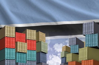 Botswana flag and big stack of shipping cargo containers in docks with sky background close up clipart