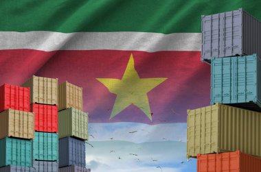 Suriname flag and big stack of shipping cargo containers in docks with sky background close up clipart