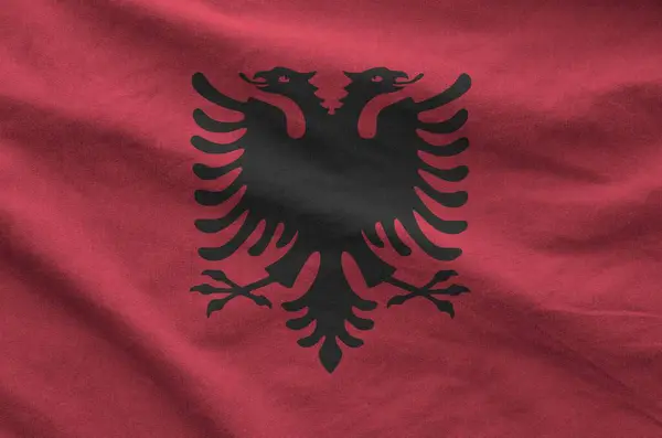 stock image Albania flag depicted on folded wavy fabric of old cloth close up