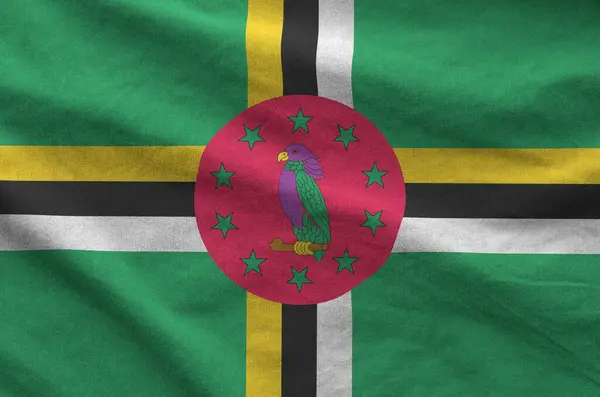 stock image Dominica flag depicted on folded wavy fabric of old cloth close up