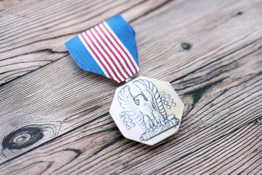 KYIV, UKRAINE - JULY 10, 2024 US Non-Combat Heroism Soldiers medal. United States military award medal with ribbon and pin. Handmade paper theater props close up clipart