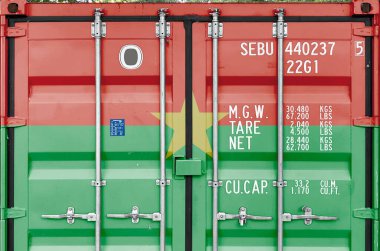 Burkina Faso flag depicted on metal doors of shipping cargo container outdoors in docks area close up clipart