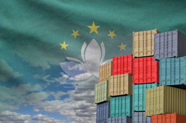 Macau flag and big stack of shipping cargo containers in docks with sky background close up clipart