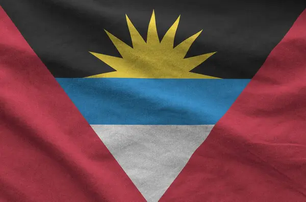 stock image Antigua and Barbuda flag depicted on folded wavy fabric of old cloth close up