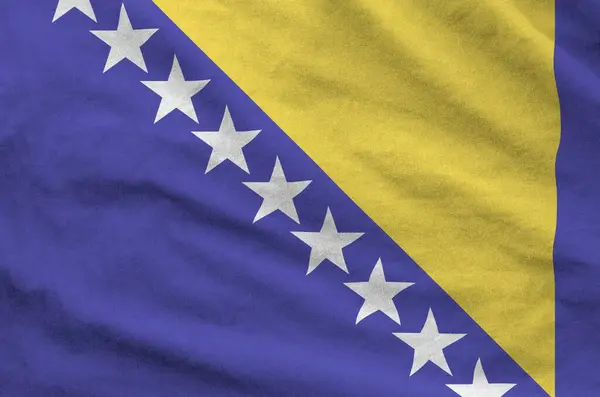 stock image Bosnia and Herzegovina flag depicted on folded wavy fabric of old cloth close up