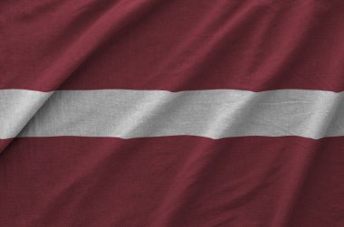 Eski kumaşın kıvrımlı kumaşında Letonya bayrağı tasvir edilmiştir.