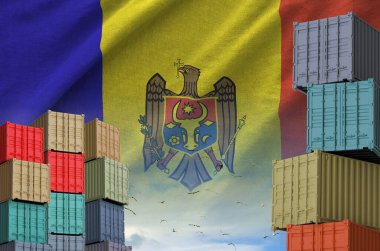 Moldova flag and big stack of shipping cargo containers in docks with sky background close up clipart