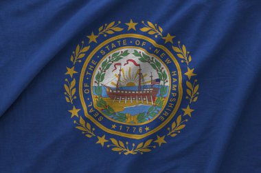 New Hampshire US state flag depicted on folded wavy fabric of old cloth close up clipart