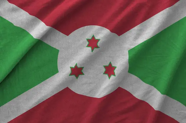 stock image Burundi flag depicted on folded wavy fabric of old cloth close up