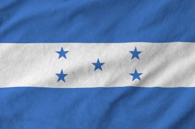 Honduras flag depicted on folded wavy fabric of old cloth close up clipart