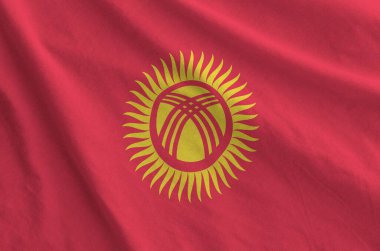 Kyrgyzstan flag depicted on folded wavy fabric of old cloth close up clipart