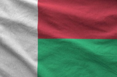 Madagascar flag depicted on folded wavy fabric of old cloth close up clipart