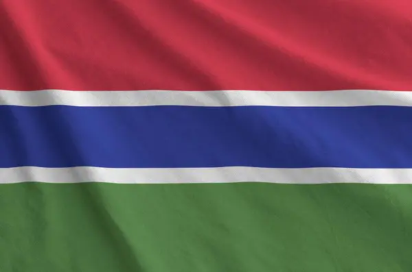 stock image Gambia flag depicted on folded wavy fabric of old cloth close up